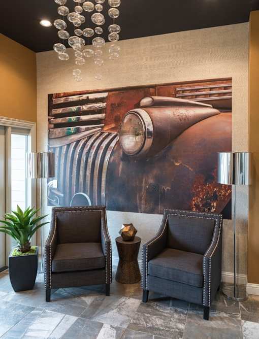 Two chairs and a table are in front of a large painting of a train.