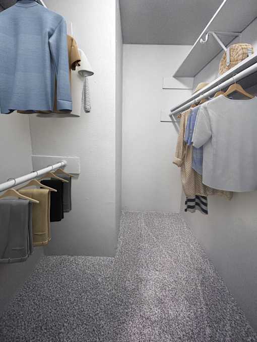 A hallway with a grey carpet and clothes hanging on the wall.