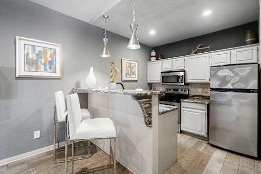A kitchen with a white chair and a marble counter.