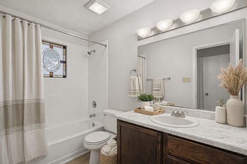 A bathroom with a white toilet, a white sink, and a white shower curtain.