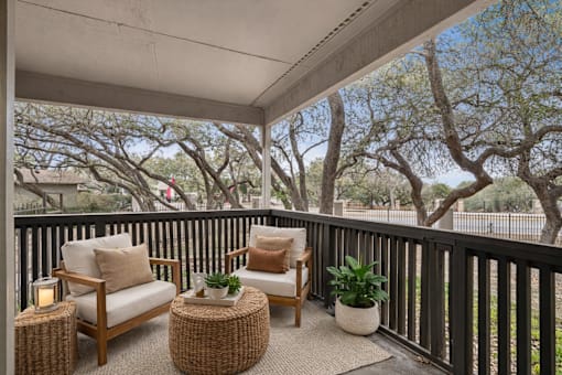A patio with a chair, a table and a potted plant.