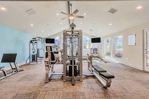 A spacious gym with a variety of equipment and a ceiling fan.