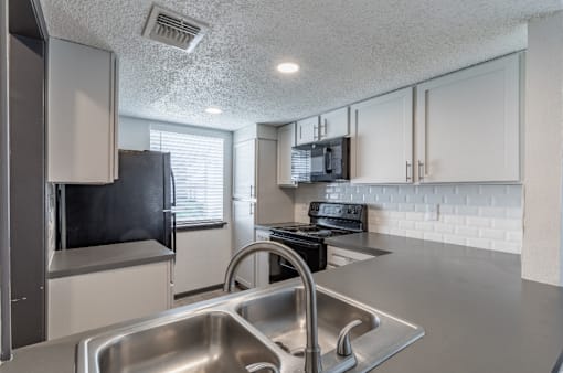a kitchen with white cabinets and stainless steel appliances at Tradewinds, Texas