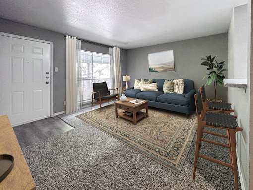 A living room with a blue couch and a rug.