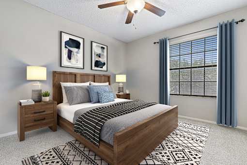 A bedroom with a large bed, a ceiling fan, and two nightstands with lamps.