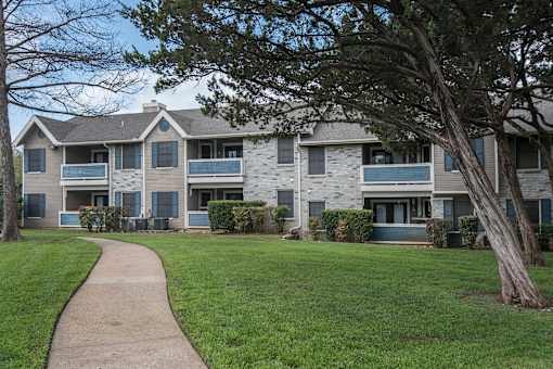 exterior view of an apartment building with a sidewalk at Polo Clubs Apartments, Austin