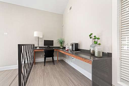 A room with a desk, chair, and a plant.