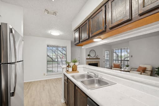 A kitchen with a stainless steel refrigerator and a marble countertop.