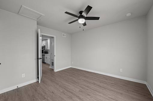 an empty living room with a ceiling fan and a door to a kitchen at Sunset Heights, San Antonio, TX