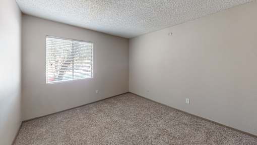 A room with a window covered by white blinds.