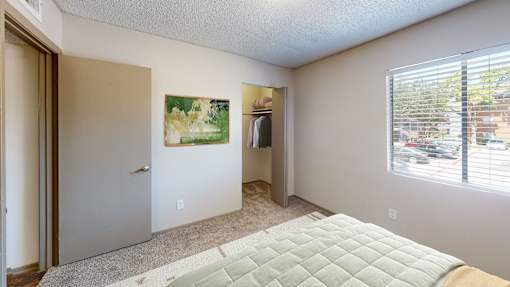 A bedroom with a bed, a painting, and a window.