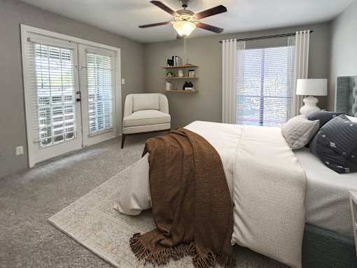 A bedroom with a bed, chair, and window.