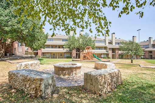A park with a stone fire pit and a playground.