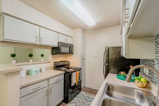 A kitchen with a black refrigerator and a stove top oven.