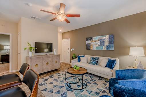 A living room with a white couch, a coffee table, and a ceiling fan.