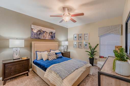 A bedroom with a large bed, a ceiling fan, and a painting on the wall.
