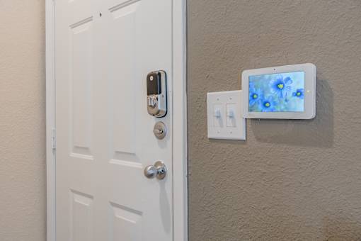 A white door with a keypad lock and a tablet on the wall.