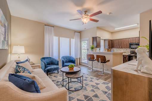 A living room with a tan couch, blue chairs, and a black and white checkered floor.