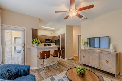 A living room with a blue couch, a wooden table, and a ceiling fan.