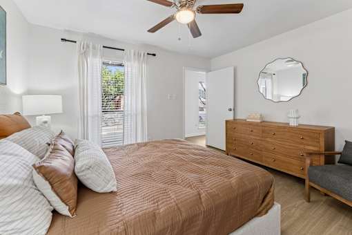 Bedroom with wood dresser and ceiling fan at Knoll Crest Apartments, San Antonio, TX
