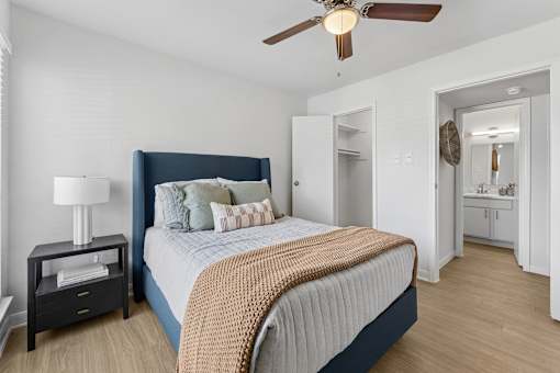 Bedroom with blue upholstered bed and en suite bathroom at Knoll Crest Apartments, San Antonio, 78240