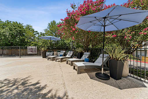 Pool deck with lounge chairs and umbrellas at Knoll Crest Apartments, Texas, 78240