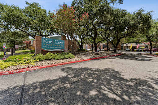 Property entrance sign with landscaping and trees at Knoll Crest Apartments, San Antonio, TX 78240