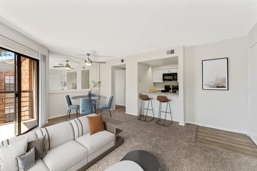 a living room with a couch a table and chairs and a kitchen in the background at The Hudson, North Richland Hills, TX