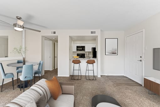 a living room with a couch and a chair in front of a kitchen with a breakfast bar at The Hudson, Texas, 76180