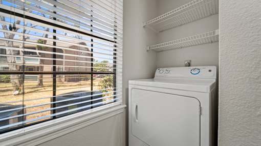 a laundry room with a washer and dryer next to a window at Polo Clubs Apartments, Austin