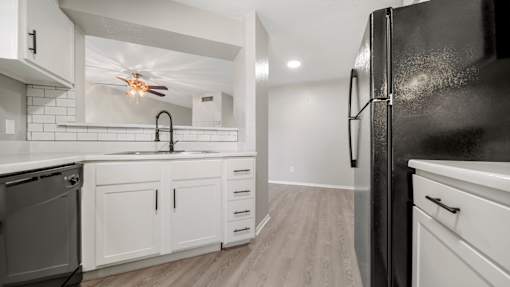 a renovated kitchen with white cabinets and a black refrigerator at Polo Clubs Apartments, Texas, 78729