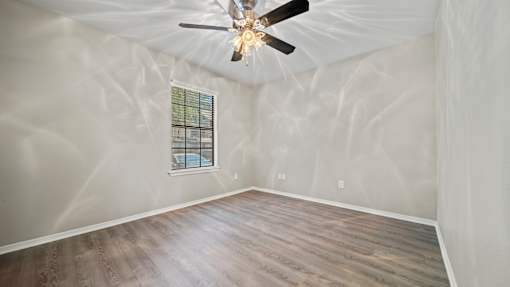 an empty bedroom with a ceiling fan and a window at Polo Clubs Apartments, Texas
