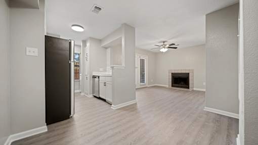an empty living room with a kitchen and a fireplace at Polo Clubs Apartments, Austin, Texas