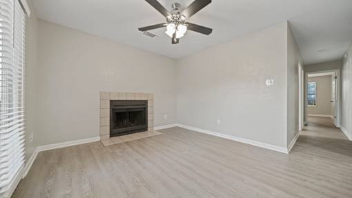an empty living room with a fireplace and a ceiling fan at Polo Clubs Apartments, Austin, TX