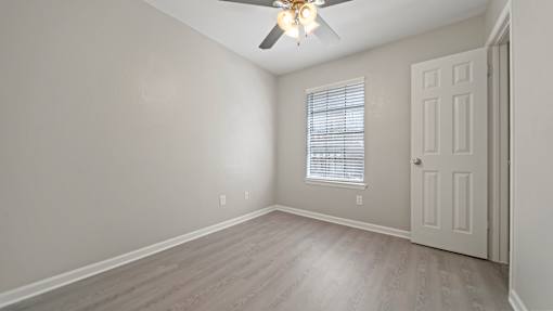 an empty bedroom with a ceiling fan and a door at Polo Clubs Apartments, Austin
