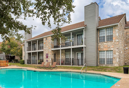 our apartments offer a swimming pool and a patio with lounge chairs at The Broadwater at Salado Creek, San Antonio, TX