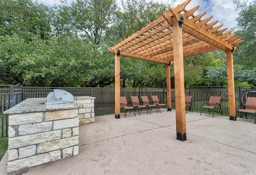 a patio with a stone fireplace and a wooden pavilion at The Broadwater at Salado Creek, San Antonio