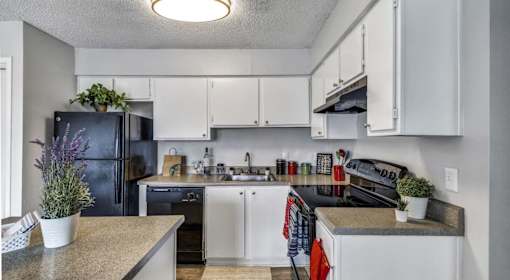 A kitchen with white cabinets and a black fridge.