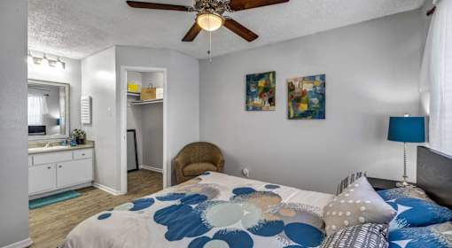 A bedroom with a bed, a chair, and a ceiling fan.