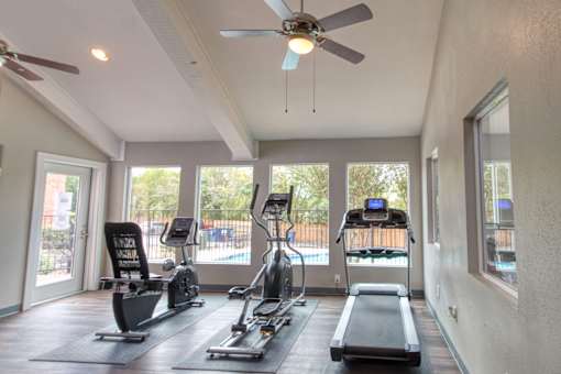 A spacious gym with a variety of equipment including treadmills, elliptical machines, and a weight bench.
