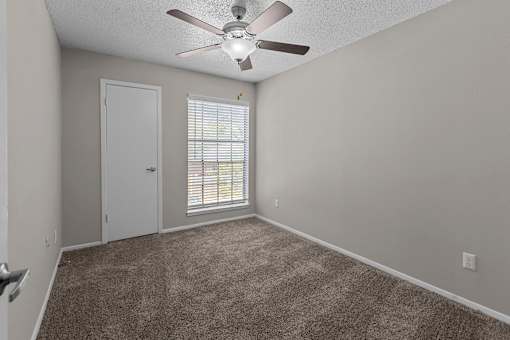 A room with a ceiling fan and carpeted floor.
