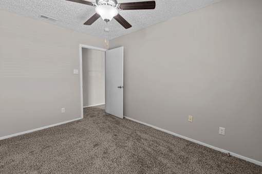 A room with a ceiling fan and carpeted floor.
