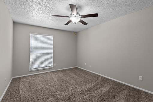 A room with a ceiling fan and a window with blinds.