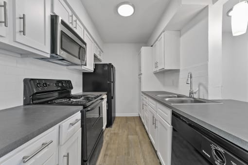 a kitchen with white cabinets and black appliances  at Vesper, Dallas, TX