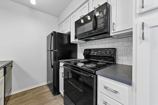 a kitchen with white cabinets and black appliances  at Vesper, Dallas, Texas