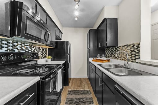 a kitchen with black cabinets and white countertops and a black and white checkered tile  at Vesper, Dallas, Texas