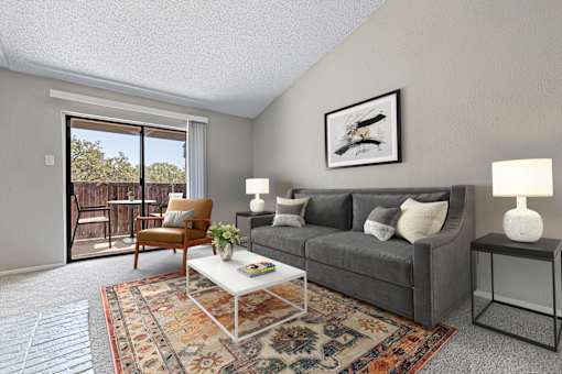 A living room with a grey couch, a coffee table, and a painting on the wall.