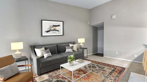 A living room with a grey couch, a coffee table, and a painting on the wall.