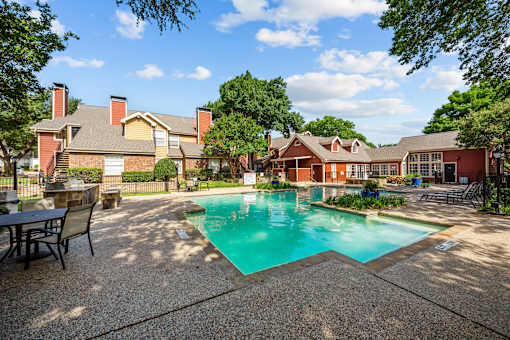 A pool surrounded by a patio and trees.