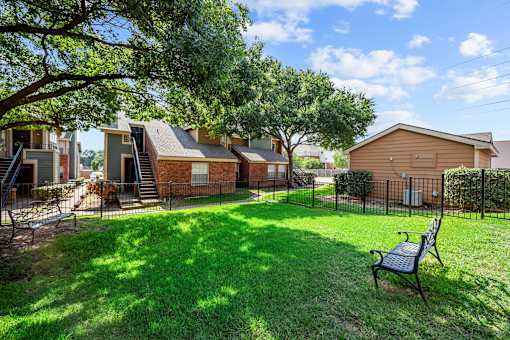 A backyard with a bench and a tree.